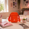 Bolso Jordan Airborne naranja lifestyle habitación adolescente Bolso Jordan Airborne naranja sobre escritorio en habitación moderna adolescente. Imagen lifestyle optimizada para Google Imágenes, Pinterest y ecommerce streetwear.