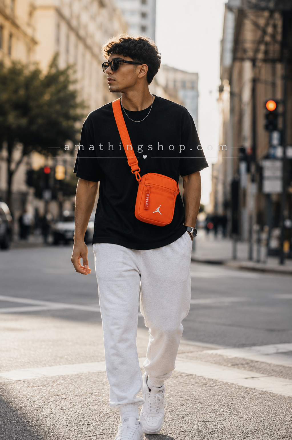 Bolso Jordan Airborne naranja hombre lifestyle urbano ciudad Hombre joven caminando por ciudad moderna usando bolso Jordan Airborne naranja estilo bandolera streetwear. Imagen lifestyle optimizada para Google Imágenes, Pinterest y ecommerce urbano.