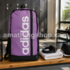 Mochila adidas Morada Mujer IZ1902 para Gimnasio y Entrenamiento Mochila adidas morada mujer original modelo IZ1902 de 22,5 litros sobre un banco de gimnasio junto a botella deportiva, auriculares y zapatillas