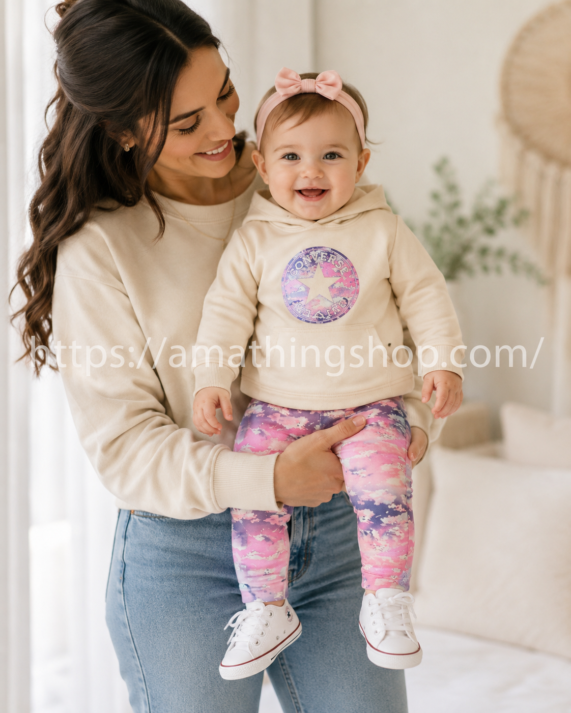 Madre sujetando bebé niña con conjunto Converse beige y leggings rosa estampado premium