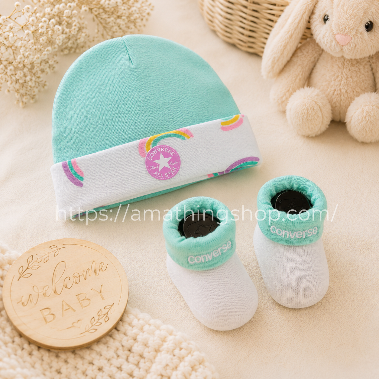 Conjunto Converse bebé turquesa con gorro arcoíris y patucos suaves presentado como regalo premium