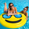 Dos chicas jóvenes usando una colchoneta piscina emoji amarilla de 150 cm con gafas de sol, flotador grande para piscina, playa, vacaciones y fotos de verano.