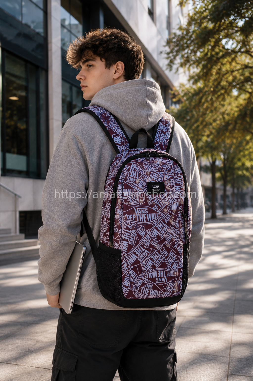Joven utilizando mochila Vans Disorder 24 litros granate con compartimento para portátil en entorno universitario urbano