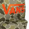 Detalle del logo Vans naranja sobre estampado camuflaje verde de la mochila Vans Old Skool Grom 18L, modelo unisex junior para colegio, instituto y estilo urbano.