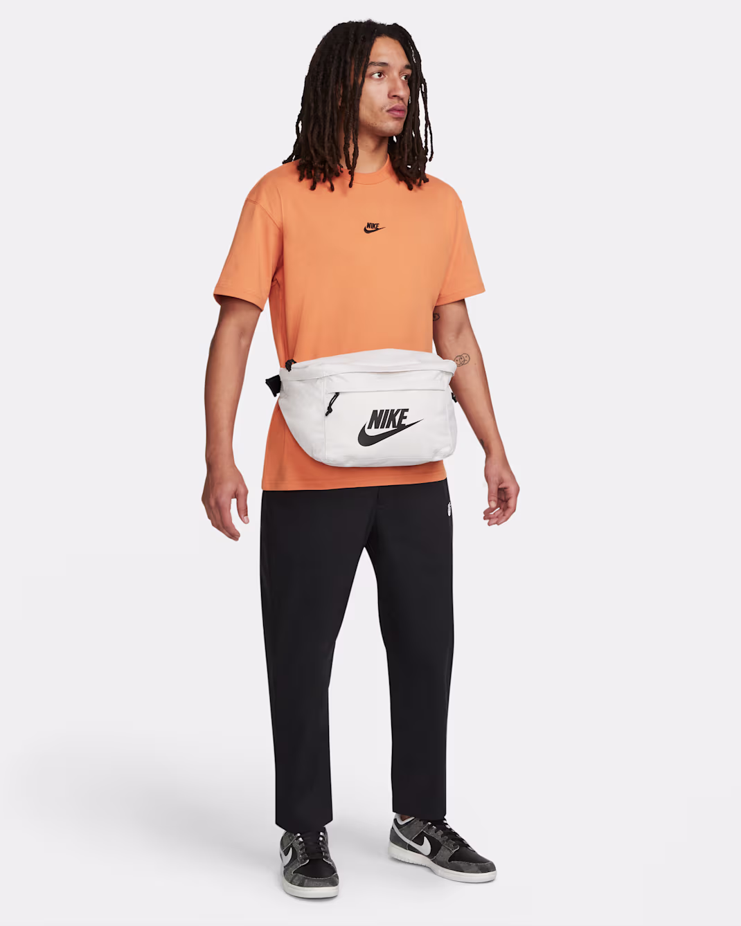 Joven usando la Nike Tech Hip Pack blanca cruzada con look urbano y streetwear