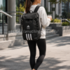 Mujer de 30 años utilizando la mochila Adidas 4ATHLTS Camper Negra HC7269 durante un paseo urbano con la mochila colocada en la espalda.
