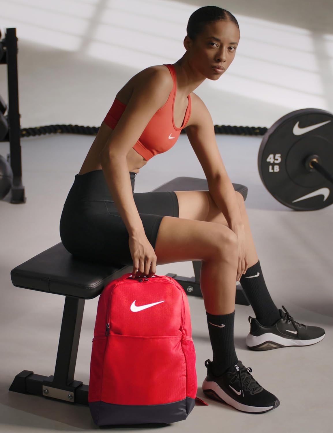 Mujer deportista con mochila Nike Brasilia 9.5 roja en gimnasio