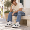 Hombre con vaqueros y camiseta clara usando Nike Air Alpha Force 88 en blanco roto, negro y verde.