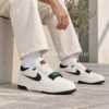 Primer plano de un hombre con pantalón crema y Nike Air Alpha Force 88 blancas con detalles negros y verdes.