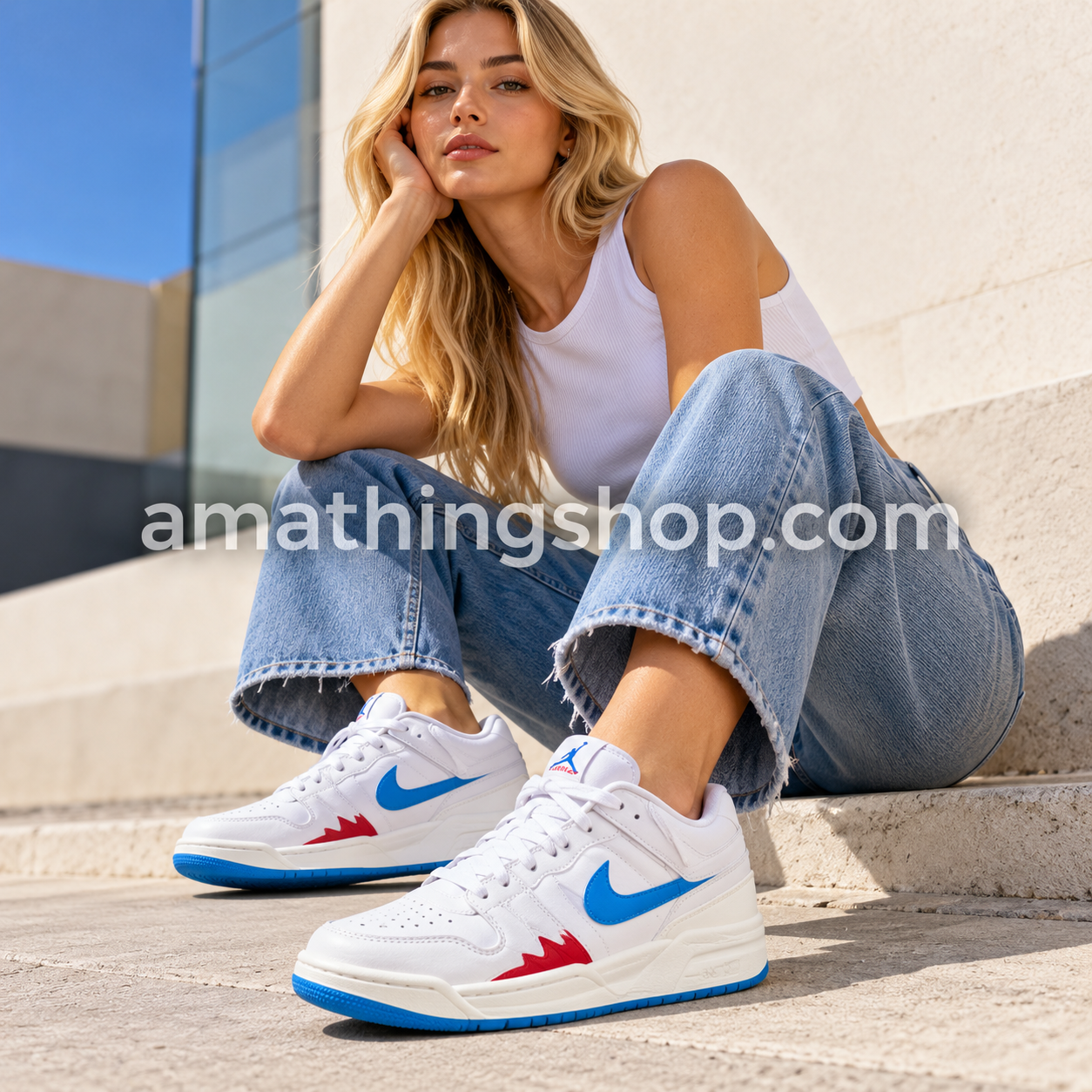 Mujer con vaqueros azules y zapatillas Jordan Stadium 90 blancas, con Swoosh azul y detalles rojos, en un look casual urbano.