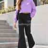Niña con pantalón de chándal Nike negro acampanado DV2564-045, logotipo violeta y zapatillas blancas en un entorno urbano