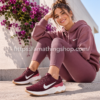 Mujer joven con sudadera lila y zapatillas Nike Renew Ride 3 burdeos sentada junto a flores moradas