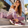 Mujer joven con zapatillas Nike Renew Ride 3 burdeos y ropa deportiva en unas escaleras urbanas